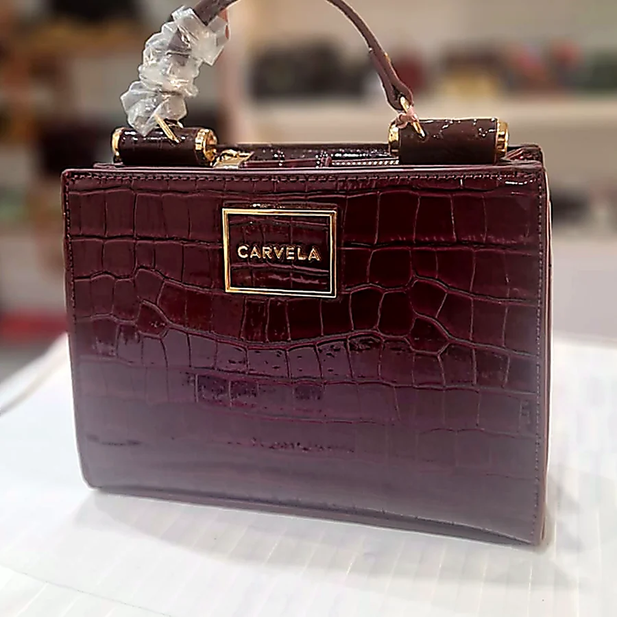 Carvela burgundy croc-effect top-handle bag on the counter in store
